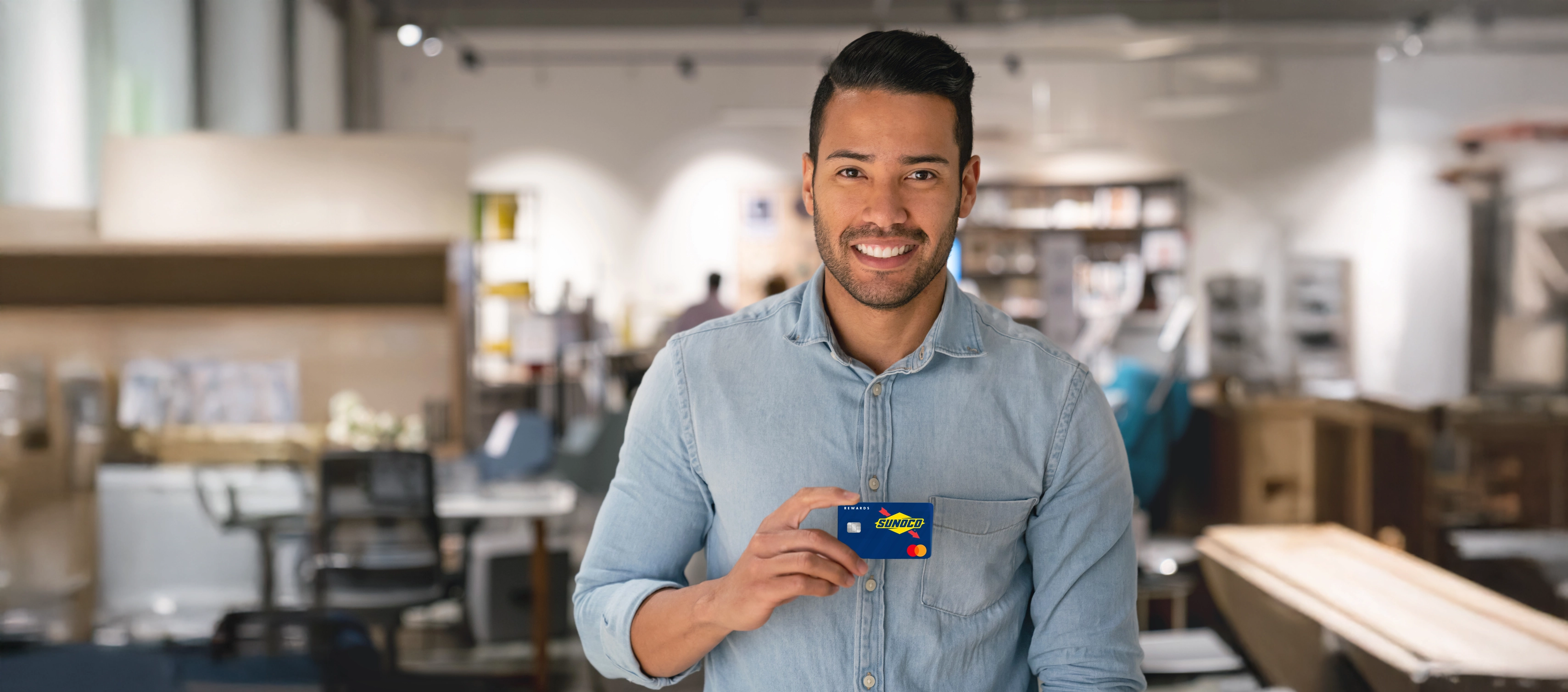 Man in store holding Sunoco credit card smiling at camera