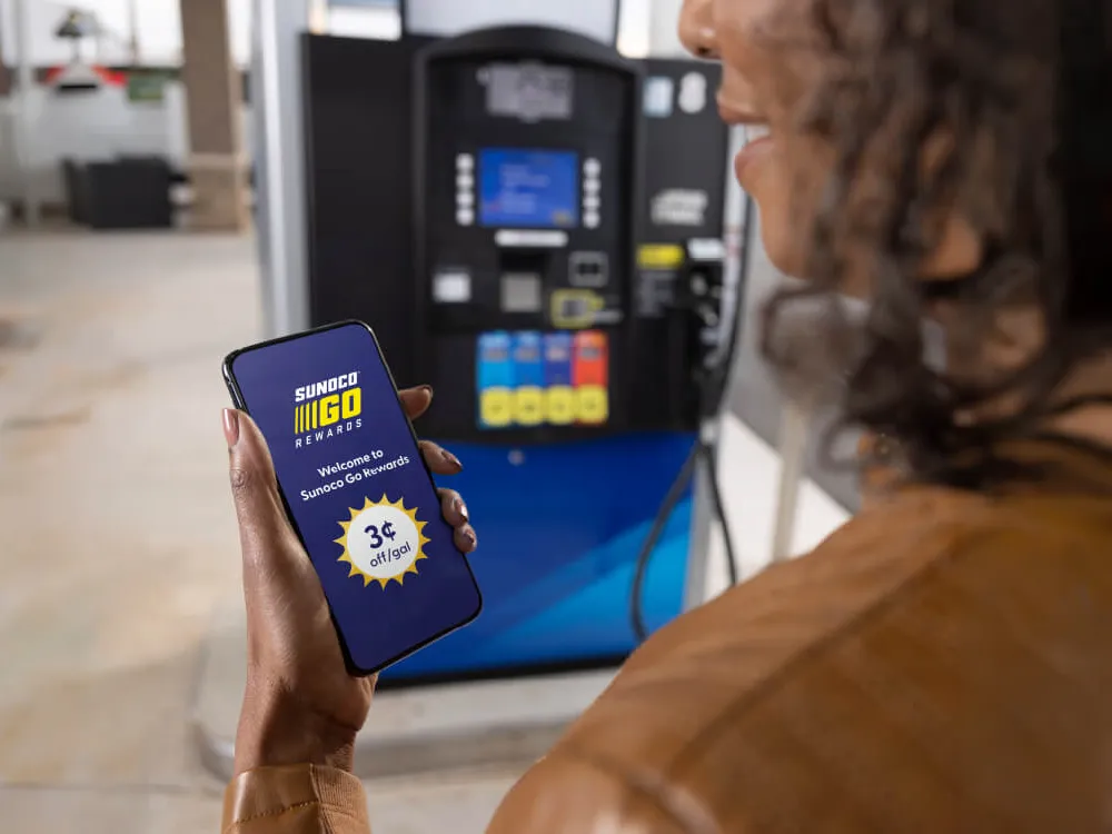 Close-up of a woman holding a smartphone displaying the Go Rewards app interface.