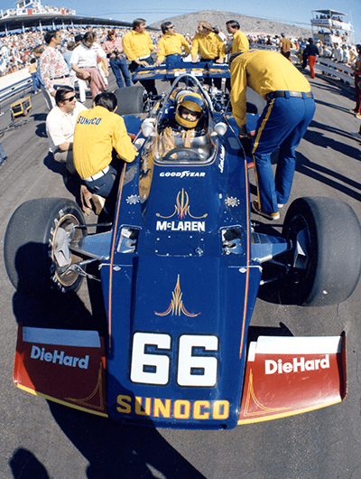 Sunoco pit crew gathered around a driver in his Sunoco-branded race car